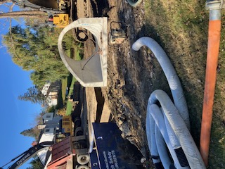 Arch culvert segment on site with temporary dewatering hoses.