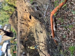 Deep excavation with dewatering line and worker in hi-vis.